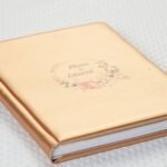 Detaliu gravură UV pe album din eco piele aurie – nume și ornament floral